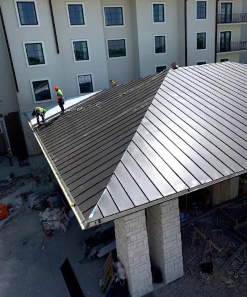 Crew installing standing seam metal roof panels on a commercial project in White Oak